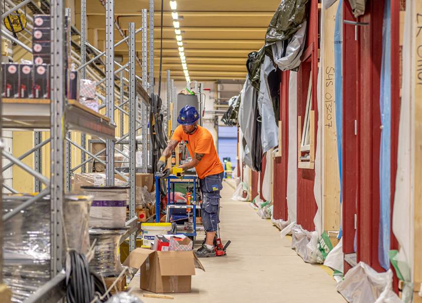 bild tagen i BoKlok fabriken i Gullringen Småland där en man står med varselkläder och bygghjälm vid ett såg